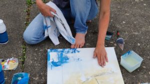 Hand beim intuitiven Malen auf Leinwand im Garten