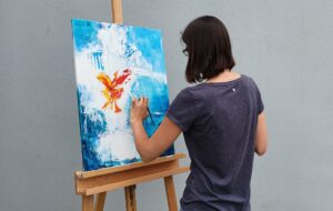 Person beim intuitiven Malen auf einer Leinwand, Rückansicht