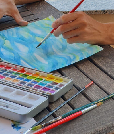 Pinsel und Aquarellfarben beim intuitiven Malen eines Wasserbildes