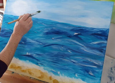 Hand mit Pinsel beim intuitiven Malen eines Wasserbildes